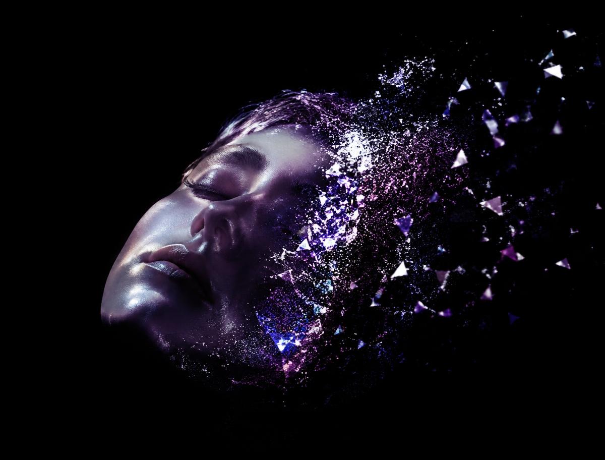 A sleeping face dissolving into drifting light particles